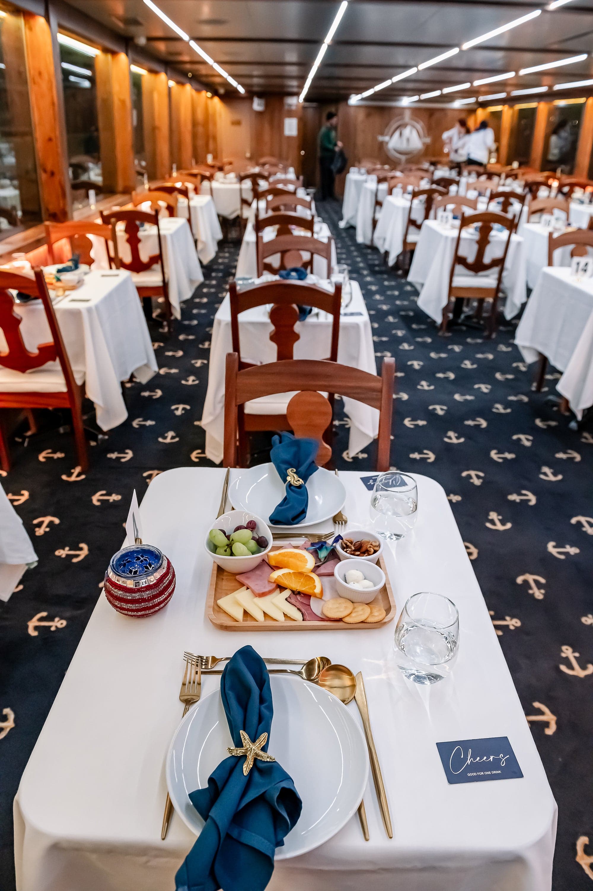 The dining saloon aboard a NYC Water Cruises vessel, tables set with white linen and gold cutlery