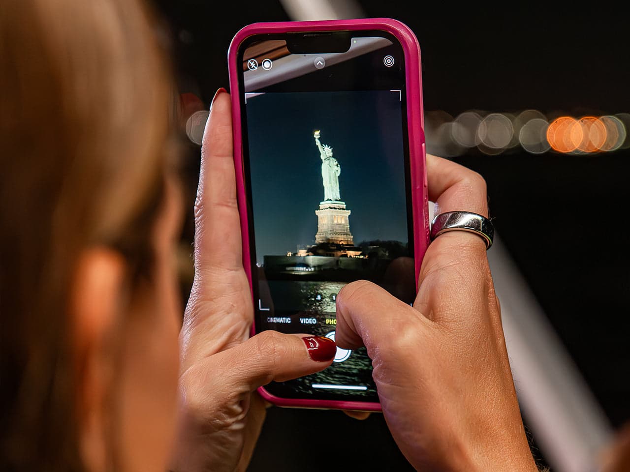 A guest photographing the Statue of Liberty from the deck at night