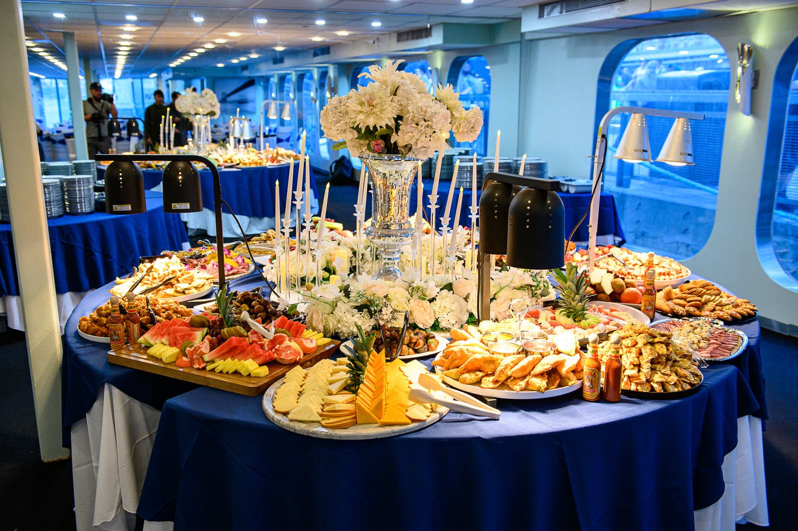 A festive holiday buffet spread aboard, with candles, white florals and the harbour visible through the windows