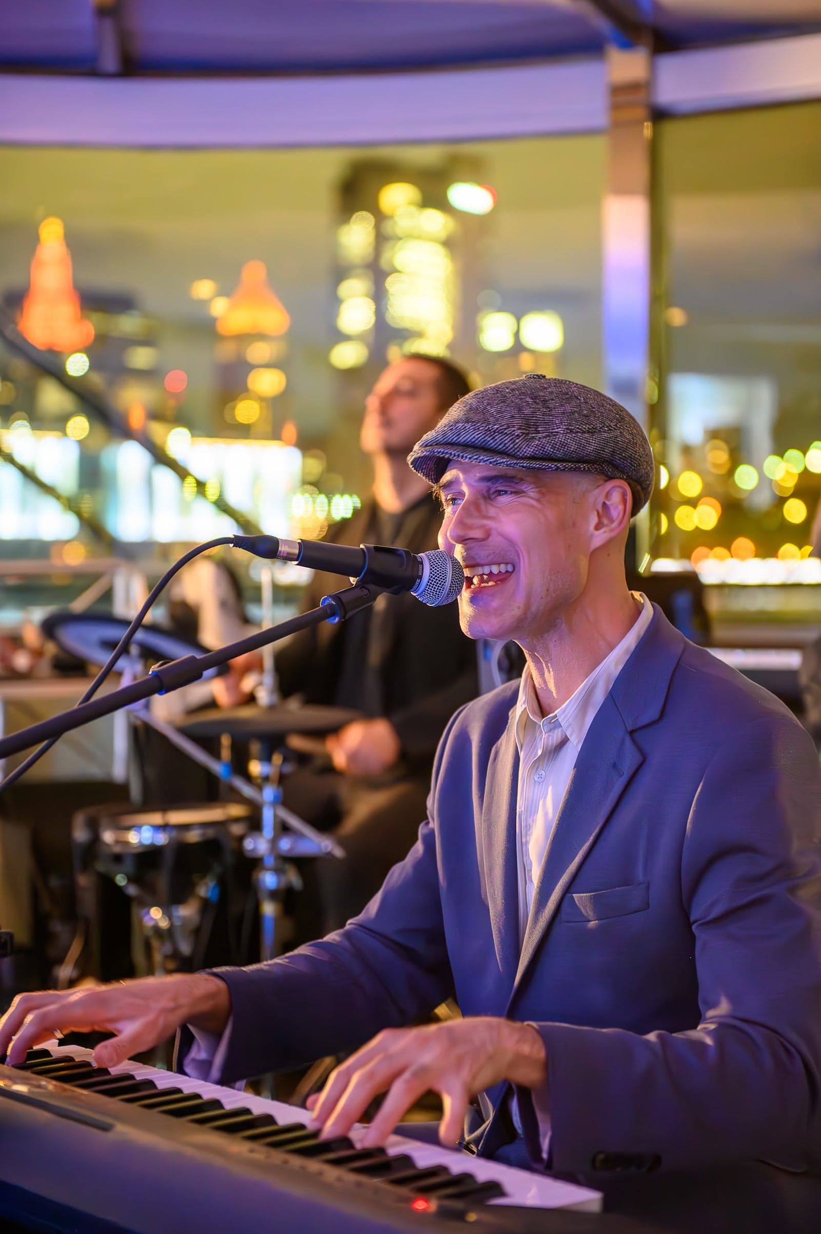 A live band performing aboard, singer at the piano with the skyline glowing behind