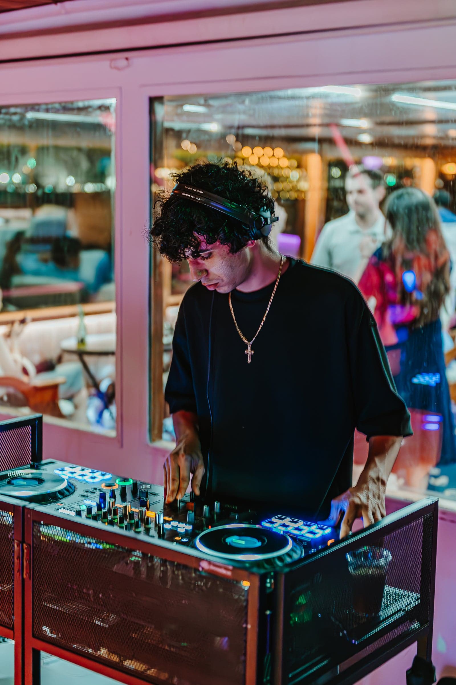 A DJ performing aboard for a holiday party, guests dancing behind glass with the harbour lit up outside