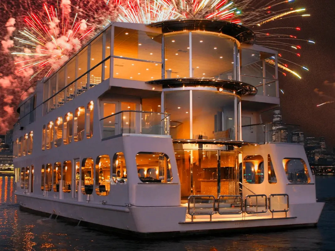 One of the vessels lit from within, fireworks bursting behind it over the harbor