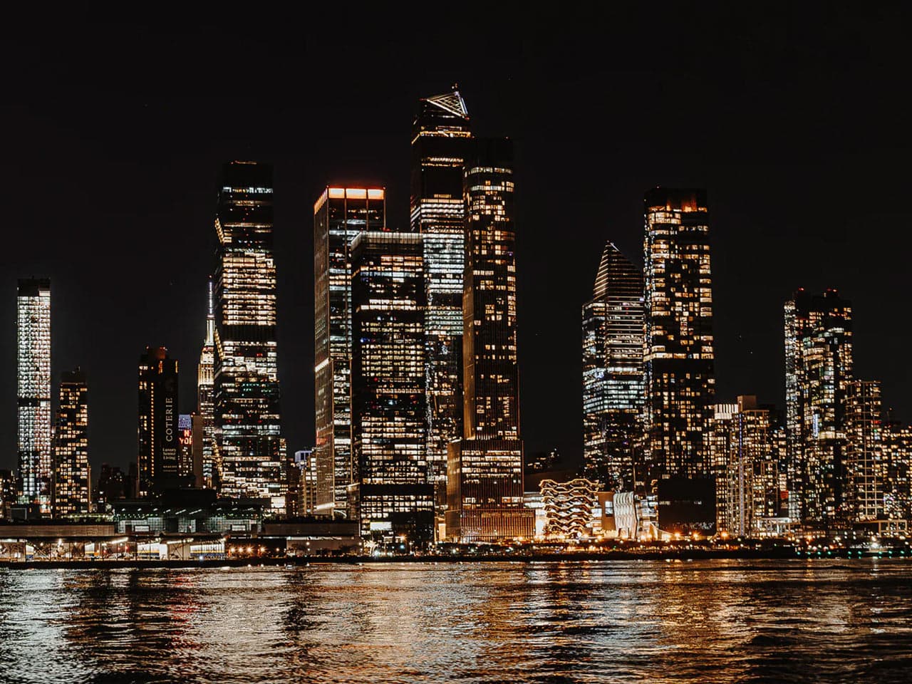 The illuminated Manhattan skyline at night, seen from the water
